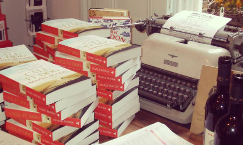 A pile of books on a table with a typewriter