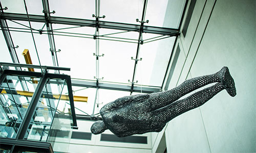 Anthony Gormley sculpture hanging from a glass ceiling in Manchester Art Gallery