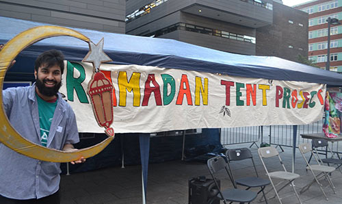 Man in front of Ramadan Tent project sign