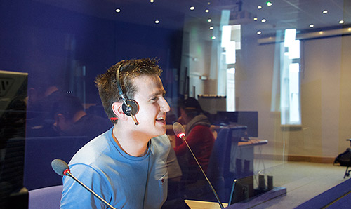 Man wearing headphones talking into microphone in a studio