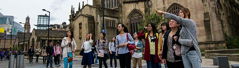 Students pointing by Manchester Cathedral