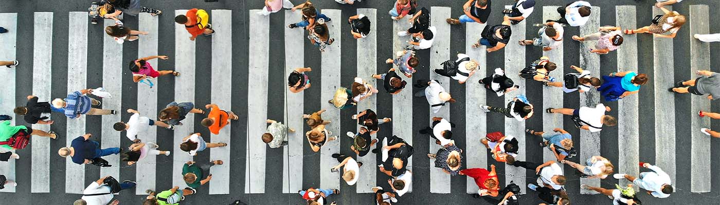 Bird's eye view of dozens of pedestrians crossing a zebra crossing.