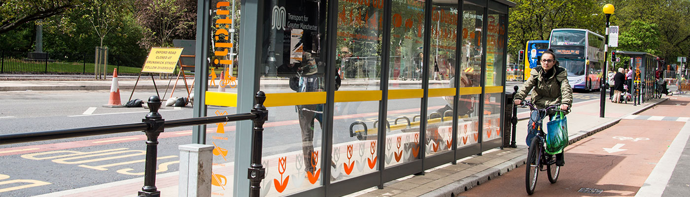 Woman riding bike next to bus stop