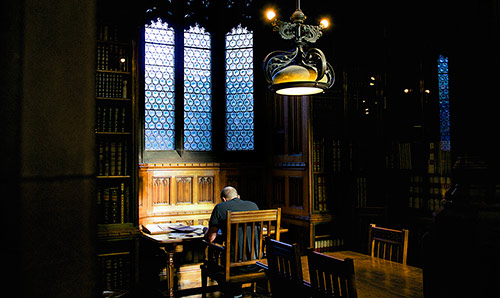 Male sat in library studying.