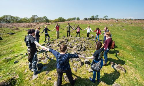 Archaeology group on a field trip holding hands in a circle.