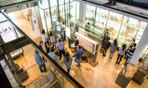 Students standing amongst Manchester Museum display cases