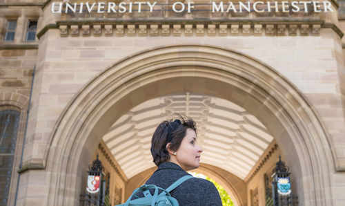 Student walking under arch of Whitworth Hall.