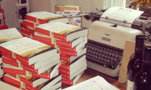 Pile of books on a desk with a typewriter