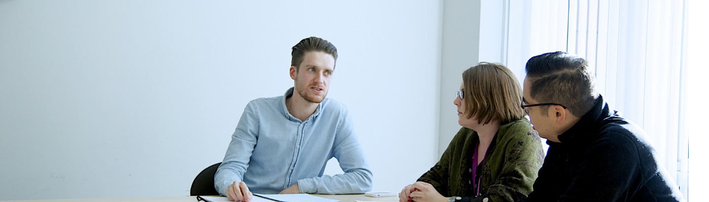 Man talking to two people sat at table