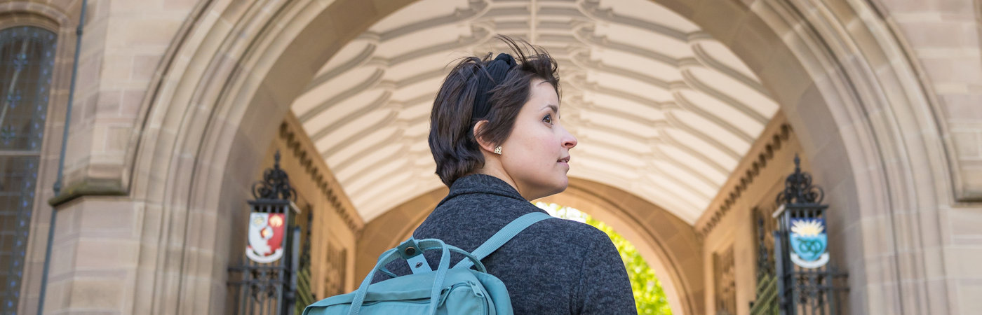 Student walking under arch of Whitworth Hall.