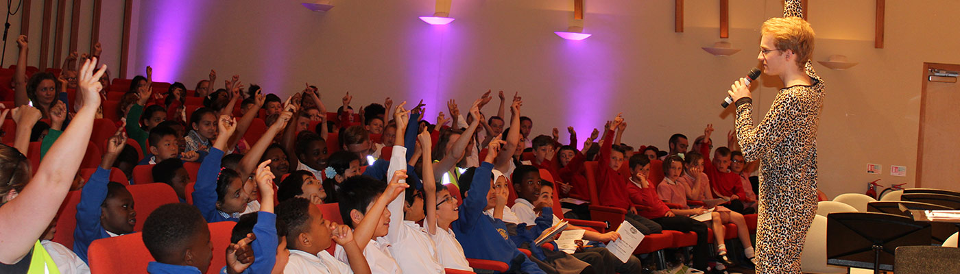 Teacher talking to school pupils with their hands up