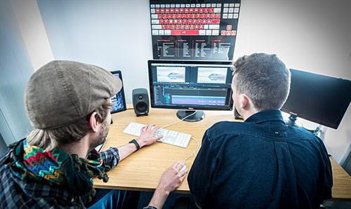 Two male students sat in front of media editing equipment