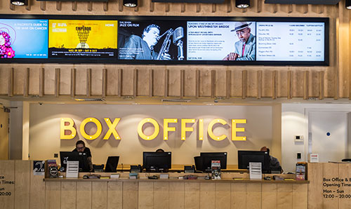 Sign on wall in yellow that says Box Office