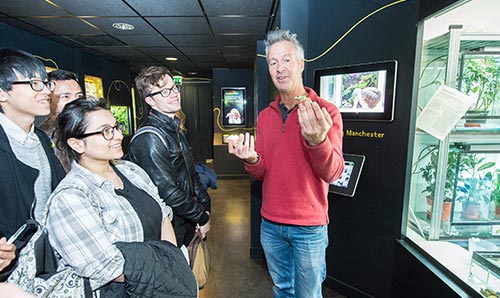 Man holding lizard doing demonstration to students in museum