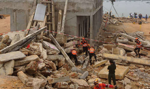 Aid workers in a building that has been affected by an earthquate, rubble.