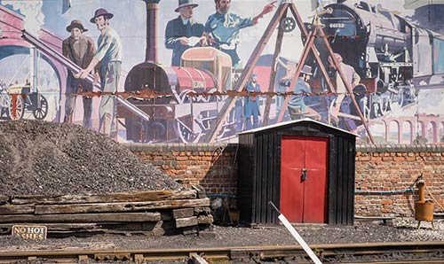 Painted scene of the history of transport on a brick wall next to train track