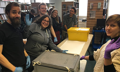 students with art-handling gloves and boxes