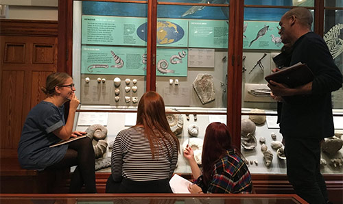 Man holding lizard doing demonstration to students in museum