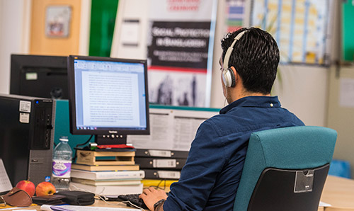 Man sat at desk on computer with headphones on