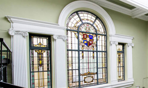 Church-style moasaic window with UCAE logo