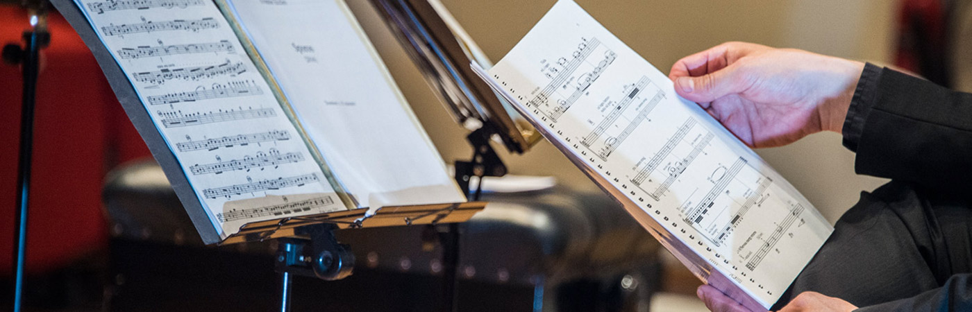 Close-up image of hands holding a sheet of music.