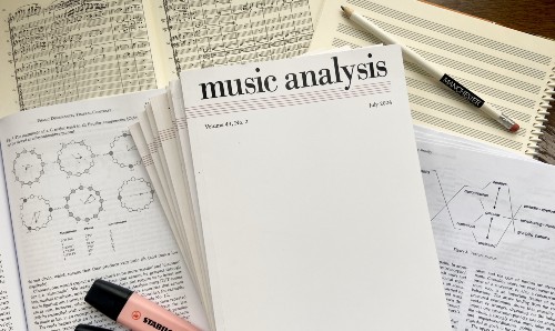 Stack of academic papers and open music theory books on a desk