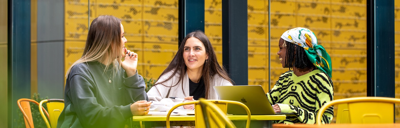 Three female students chatting outside HOME.