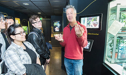 Man holding lizard doing demonstration to students in museum