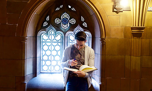 Student reading in front of pane glass window