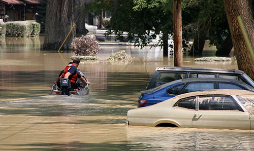 Flooded area with cars underwater and support worker in rescue boat