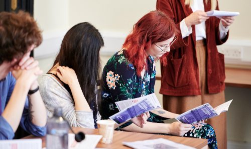 Three students sat reading pamphlets 