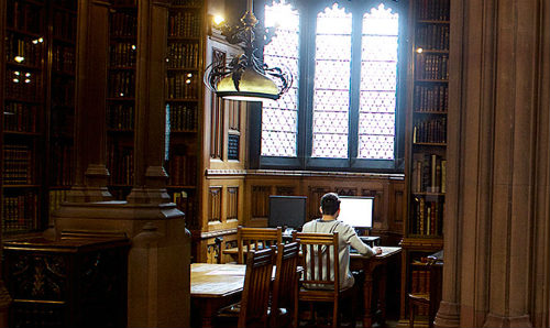 student at laptop in wood panelled library
