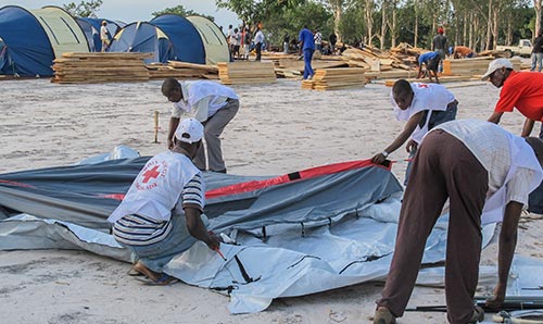 Red Cross workers putting up a tent in a new refugee camp in Congo, Central Africa / Editorial Credit: Chris Warham / Shutterstock.com