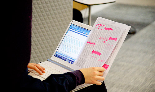 Laptop on students lap with notes next to it