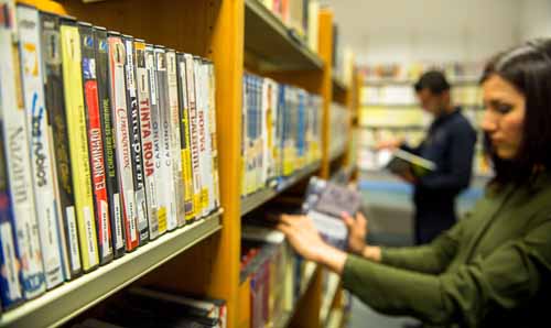 girl at dvd shelves of library