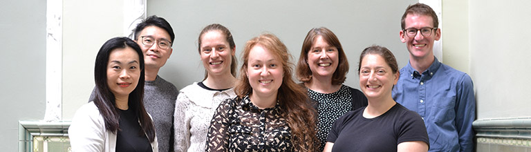 A group of staff members standing closely together and smiling at the camera